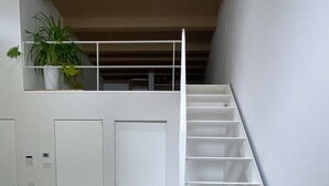 Ein modernes Interieur mit einer weißen Treppe, einem Blumentopf und einem weißen, flauschigen Gegenstand auf dem Boden.