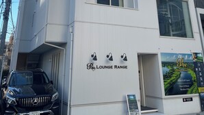 Ein modernes Gebäude mit einem Schild für 'Lounge Range' und einem Mercedes-Benz SUV davor geparkt.