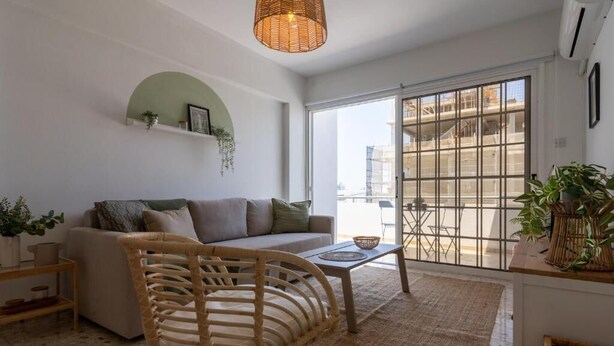 A modern living room with a sofa, wicker chair, and a coffee table. - Blossom 1-BR Apt. & Balcony in Larnaca (Larnaca)