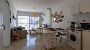 A modern kitchen with a central island, a washing machine, and a dining area with a sofa and chairs. - Blossom 1-BR Apt. & Balcony in Larnaca (Larnaca)