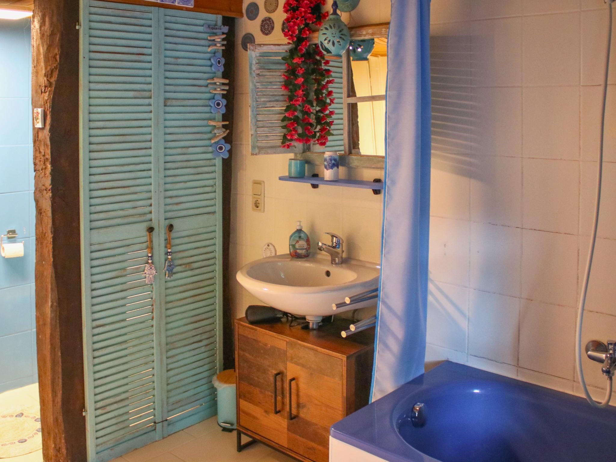 Un baño con un armario de madera, un lavamanos y una bañera azul.