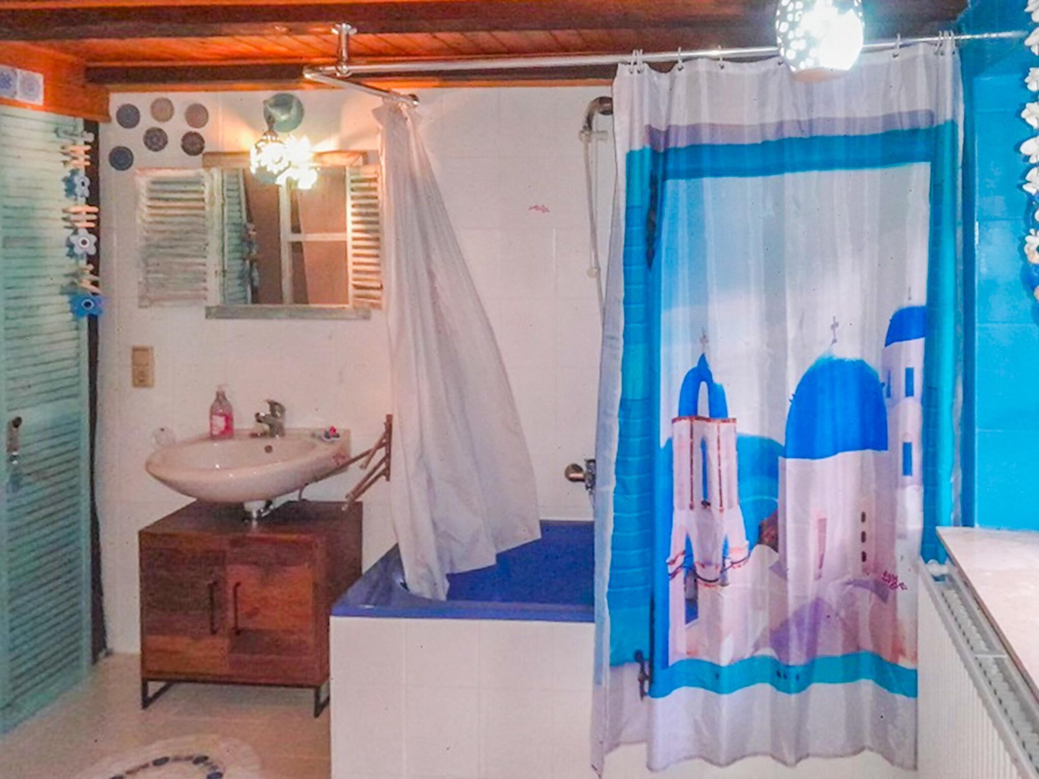 A bathroom with a sink, mirror, and a shower curtain with a blue and white design.