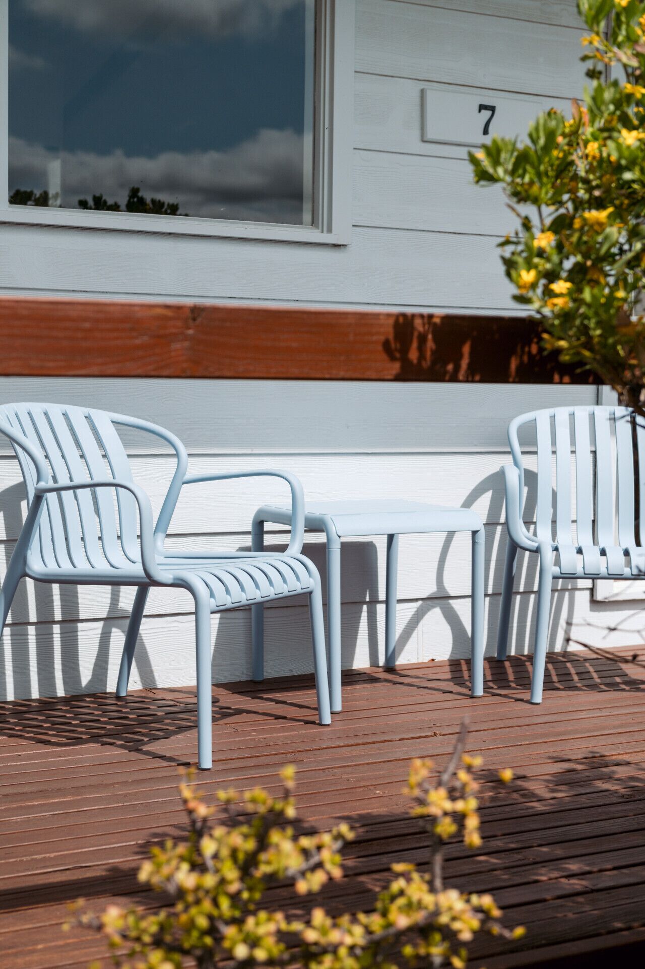 Une terrasse en bois avec deux chaises en métal blanc et une petite table.