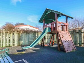 Une structure de jeu en bois, dotée d’un toboggan et d’une zone d’escalade.