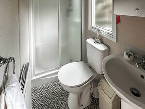 Une salle de bain comprenant des toilettes, un lavabo et un espace douche.