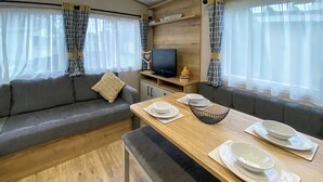Un intérieur de camping-car moderne, avec un canapé, une table à manger et un téléviseur.