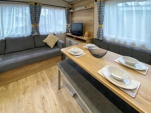 Un interior moderno de autocaravana con sofá, mesa de comedor y televisión.