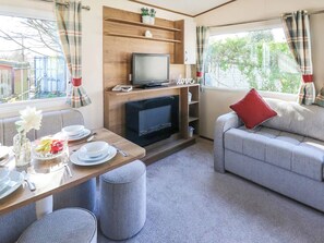 Een gezellige woonkamer met een televisie, een bank en een eethoek.