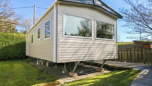 Une maison mobile dotée d’un toit plat, de grandes fenêtres et d’un petit espace porche.