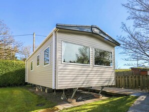 Una casa móvil con techo plano, ventanas amplias y un pequeño porche.