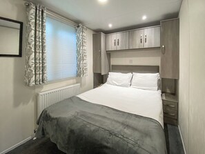 Une chambre à coucher avec un lit, un radiateur, des rideaux et une armoire.