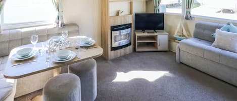 Un salon meublé comprenant un canapé, un téléviseur, une table à manger et une cheminée.