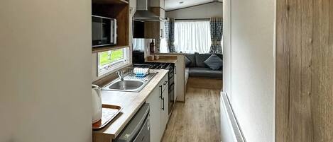A compact kitchen with a dishwasher, microwave, and stove.
