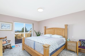 Une chambre à coucher comprenant un lit, une table de chevet, une chaise, une fenêtre et une vue sur l’extérieur.