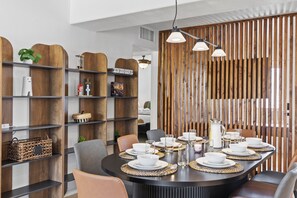 Un comedor moderno con una mesa redonda dispuesta para cuatro personas, rodeado de estanterías de madera y un panel vertical de madera.
