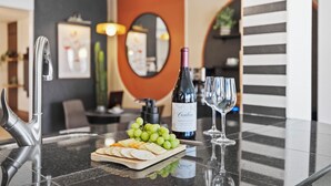 A modern kitchen with a wine bottle, glasses, and a cheese board.