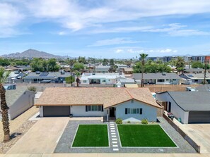 Un barrio residencial con casas, cielo despejado y una montaña al fondo.