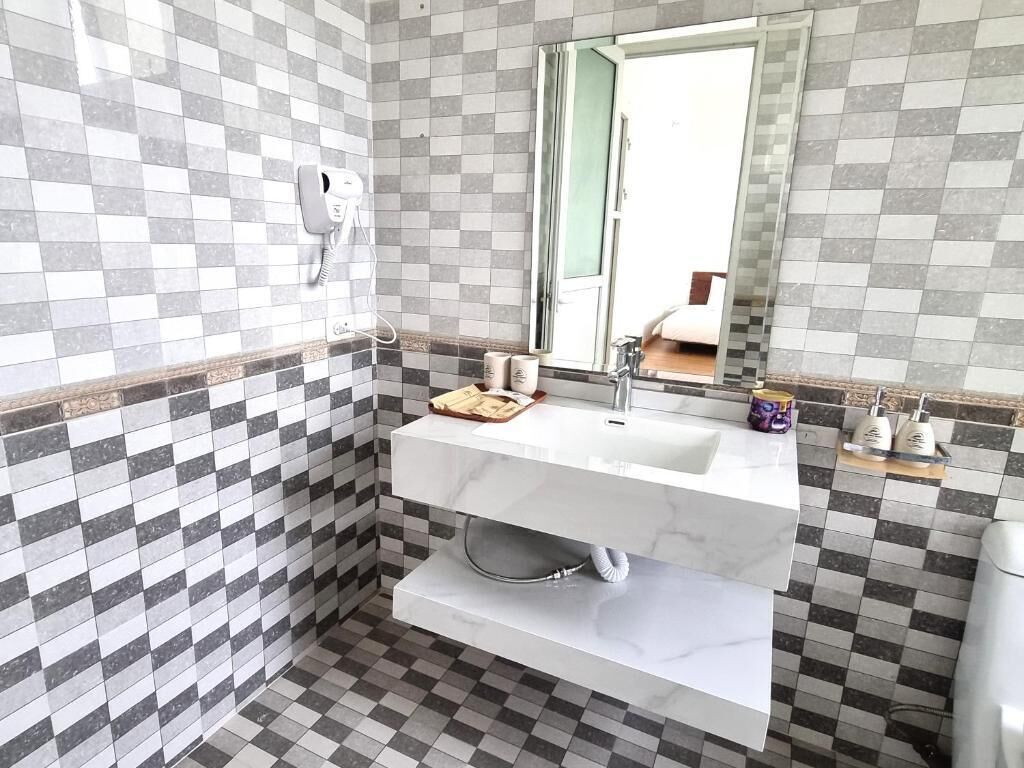 A bathroom with a checkered tile pattern, a white sink, a mirror, and a towel rack.