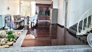 A modern kitchen with dark tiles, a dining area with chairs, and a staircase with a railing. - Top Hill Halong Homestay (Bai Chay)