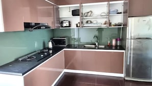 A compact kitchen with a gas stove, microwave, and a stainless steel refrigerator. - Top Hill Halong Homestay (Bai Chay)