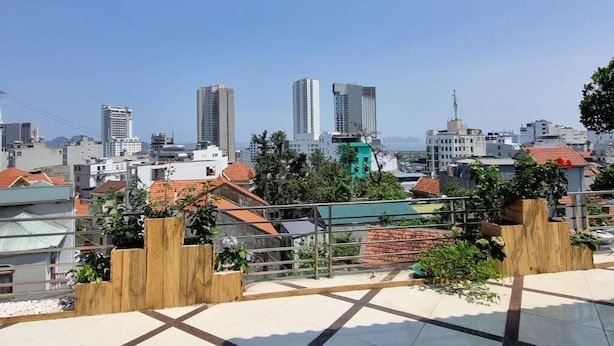A rooftop terrace with a cityscape view, including high-rise buildings and greenery. - Top Hill Halong Homestay (Bai Chay)