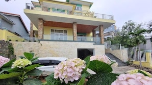 A two-story house with a balcony, surrounded by large hydrangea plants. - Top Hill Halong Homestay (Bai Chay)