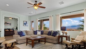 A spacious living room with a sectional sofa, a coffee table, and a view of the mountains through large windows.