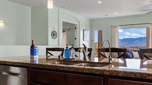 A kitchen with granite countertops, stainless steel appliances, and a view of mountains through large windows.