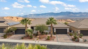 A residential area with houses featuring sloped roofs, solar panels, and palm trees.