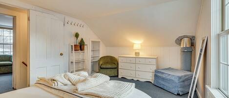 A bedroom with a bed, a dresser, a chair, and a radiator.