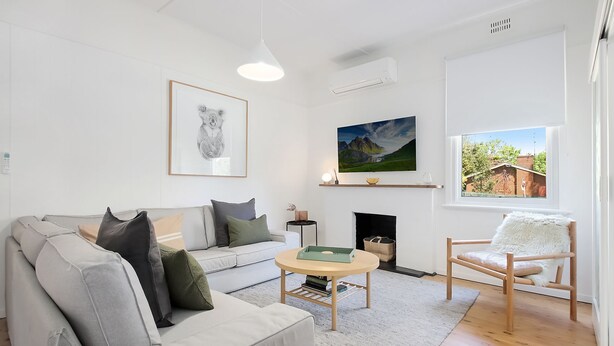 A modern living room with a sofa, a chair, a fireplace, and artwork on the walls.