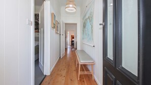 A hallway with wooden flooring, white walls, and a bench. There are doors on both sides, and a map is hanging on the wall.