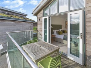 Ein Balkon mit Tisch und Stühlen, ein Bett mit Kissen und Blick zum Himmel.