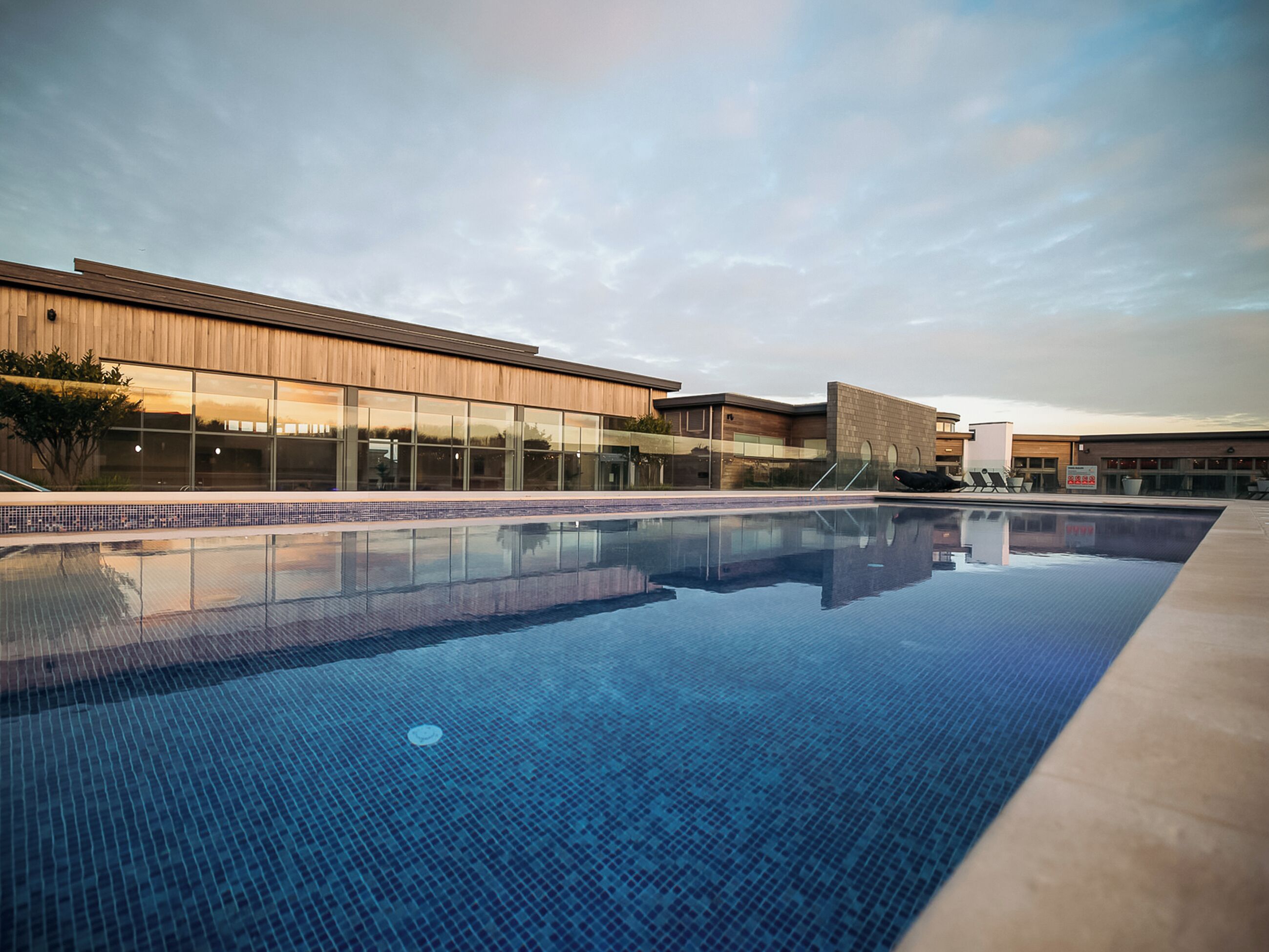 A modern building with a swimming pool in front.