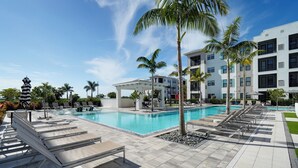 A swimming pool area with lounge chairs, palm trees, and a covered seating area. - Pool Access! Luxe Condo 7 Mi to Coquina Beach (Bradenton)