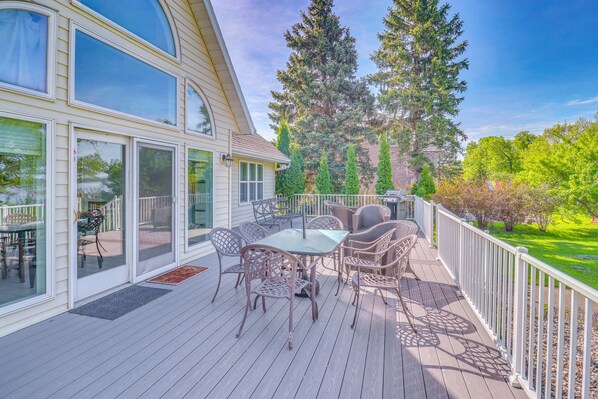 A covered deck with outdoor furniture, large windows, and a view of trees and a house. - Waterfront Alexandria Gem: Family & Group Friendly (Alexandria)