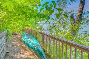 A wooden deck with a green kayak, surrounded by trees and overlooking a body of water. - Waterfront Alexandria Gem: Family & Group Friendly (Alexandria)