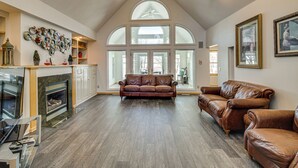 A spacious living room with a high ceiling, leather sofas, a fireplace, and large windows. - Waterfront Alexandria Gem: Family & Group Friendly (Alexandria)