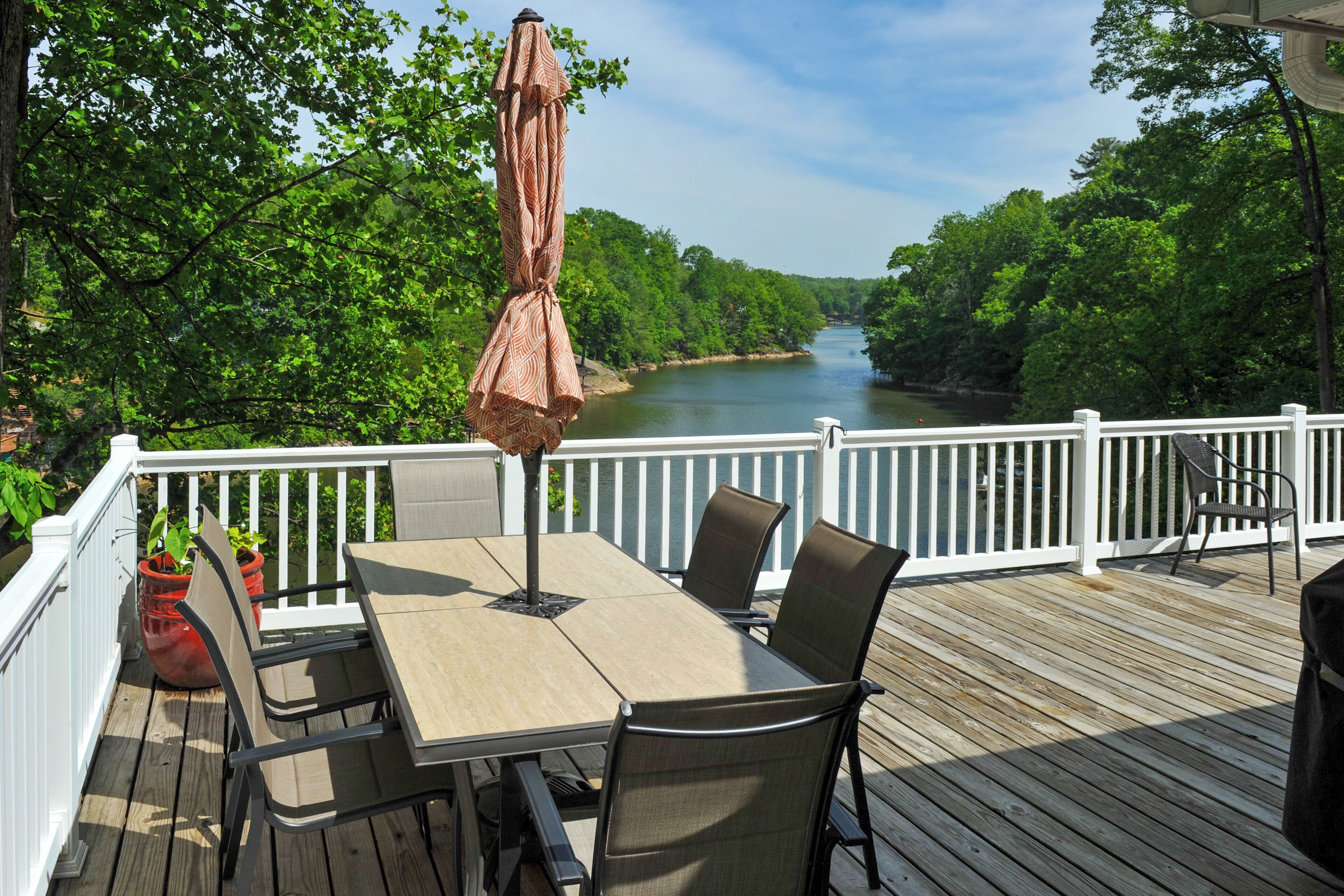 Eine Terrasse mit Tisch und Stühlen mit Blick auf einen Fluss.