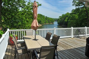 Une terrasse avec une table et des chaises, donnant sur une rivière.
