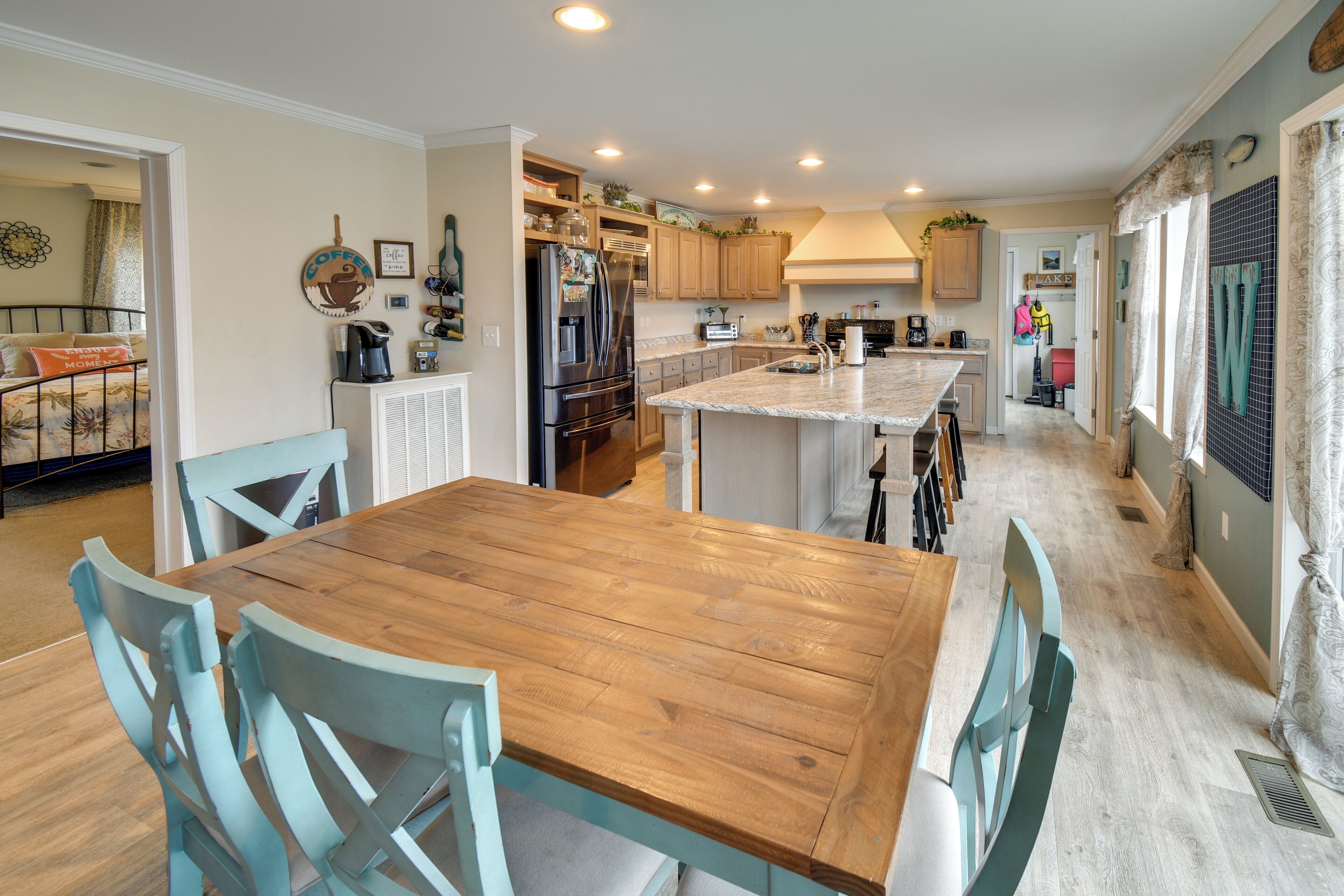A modern kitchen with a central island, wooden dining table, and light blue chairs.