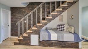 Een slaapkamer met een houten trap, een bed met een gestreept dekbed en een muur met decoratieve borden.
