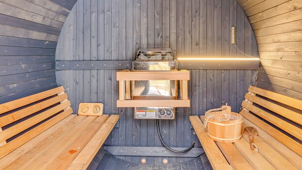 En sauna med træbænke, ovn og en træspand.