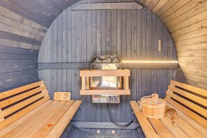 Eine Sauna mit Holzbänken, einem Saunaofen und einem Holzeimer.
