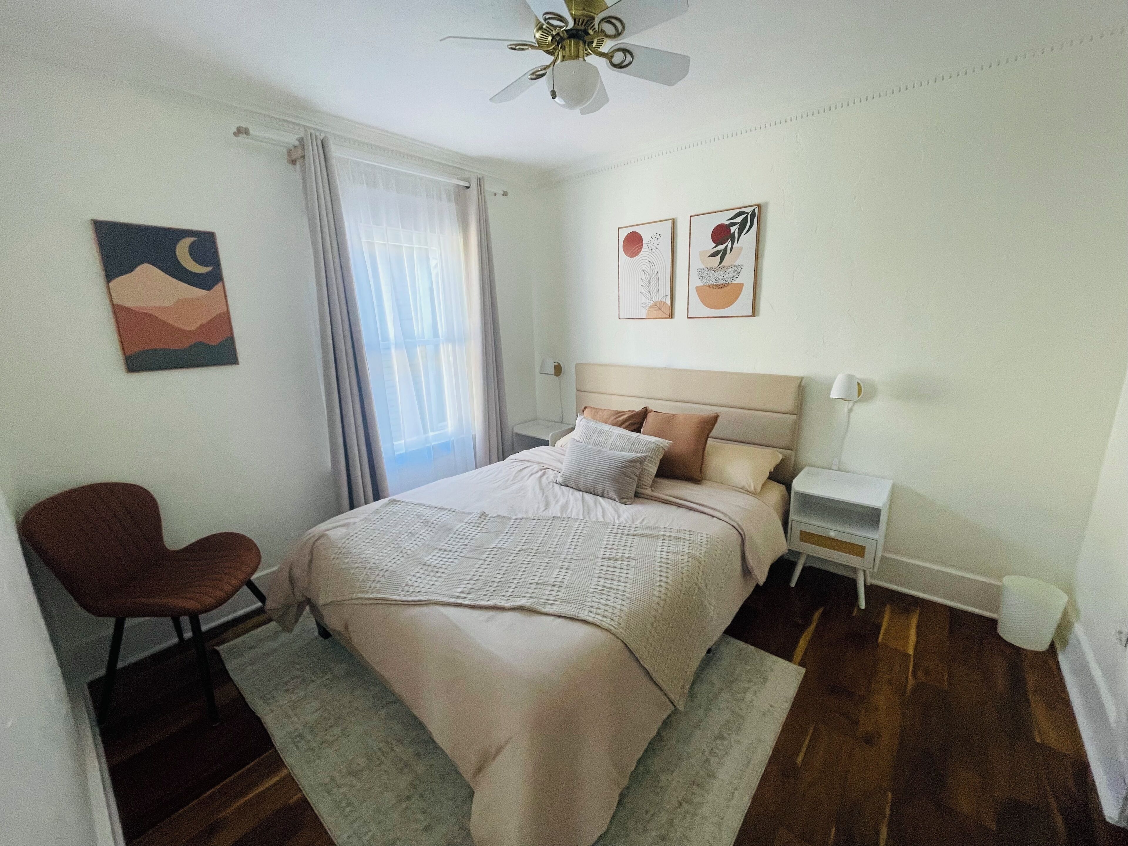 A bedroom with a bed, a chair, a nightstand, and a ceiling fan.