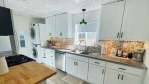 Una cocina moderna con armarios blancos, encimera de granito, lavavajillas empotrado, estufa y ventana con vistas.