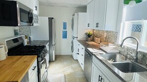 Una cocina moderna con armarios blancos, electrodomésticos de acero inoxidable y salpicadero de azulejos.