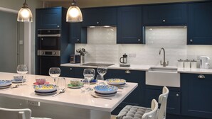 A modern kitchen with dark blue cabinets, a white countertop, and a central island with seating. - 3 bedroom accommodation in Sheringham (Sheringham)