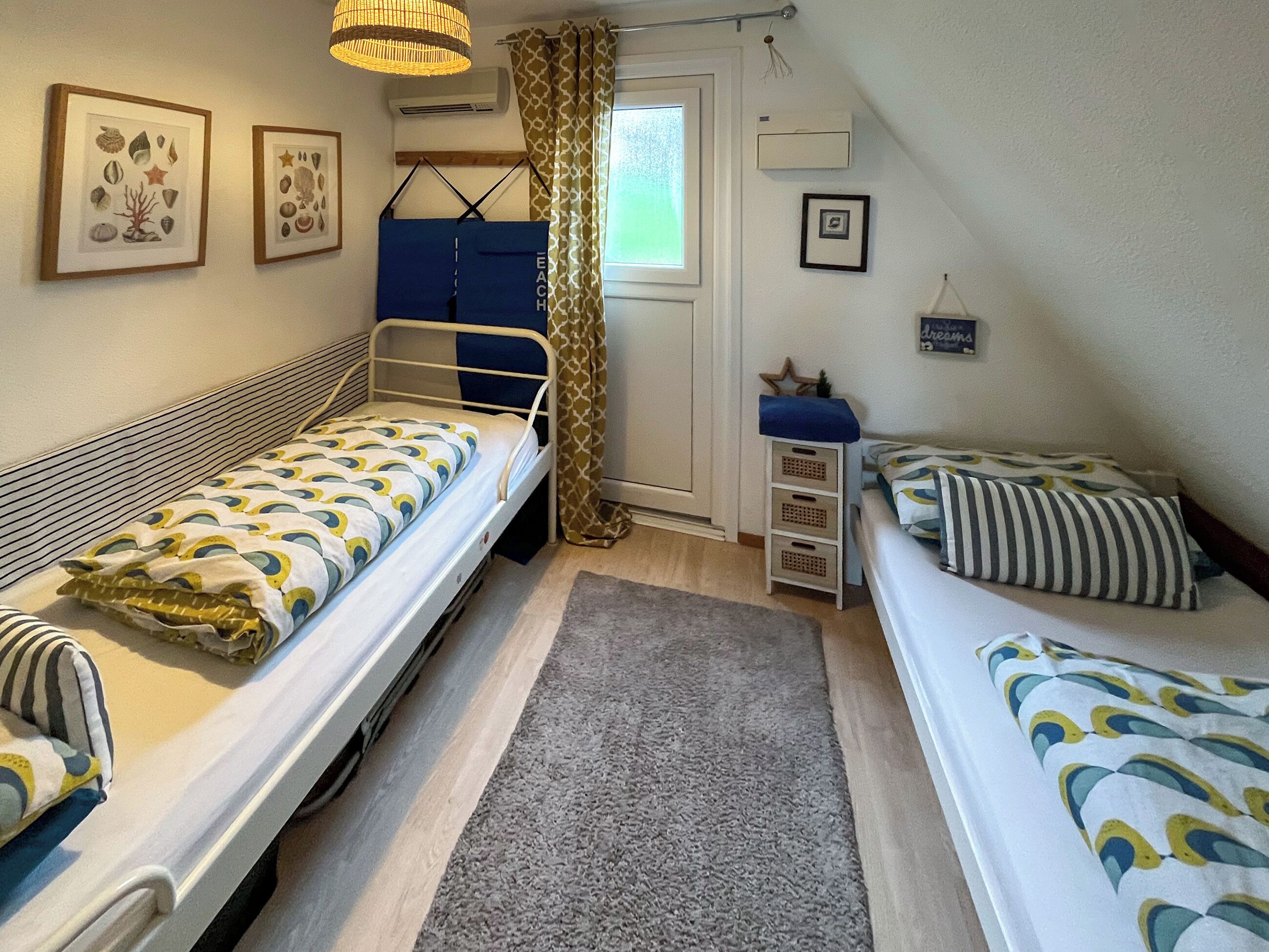 A dormitory room with two bunk beds, a small desk, a chair, and a window with curtains.