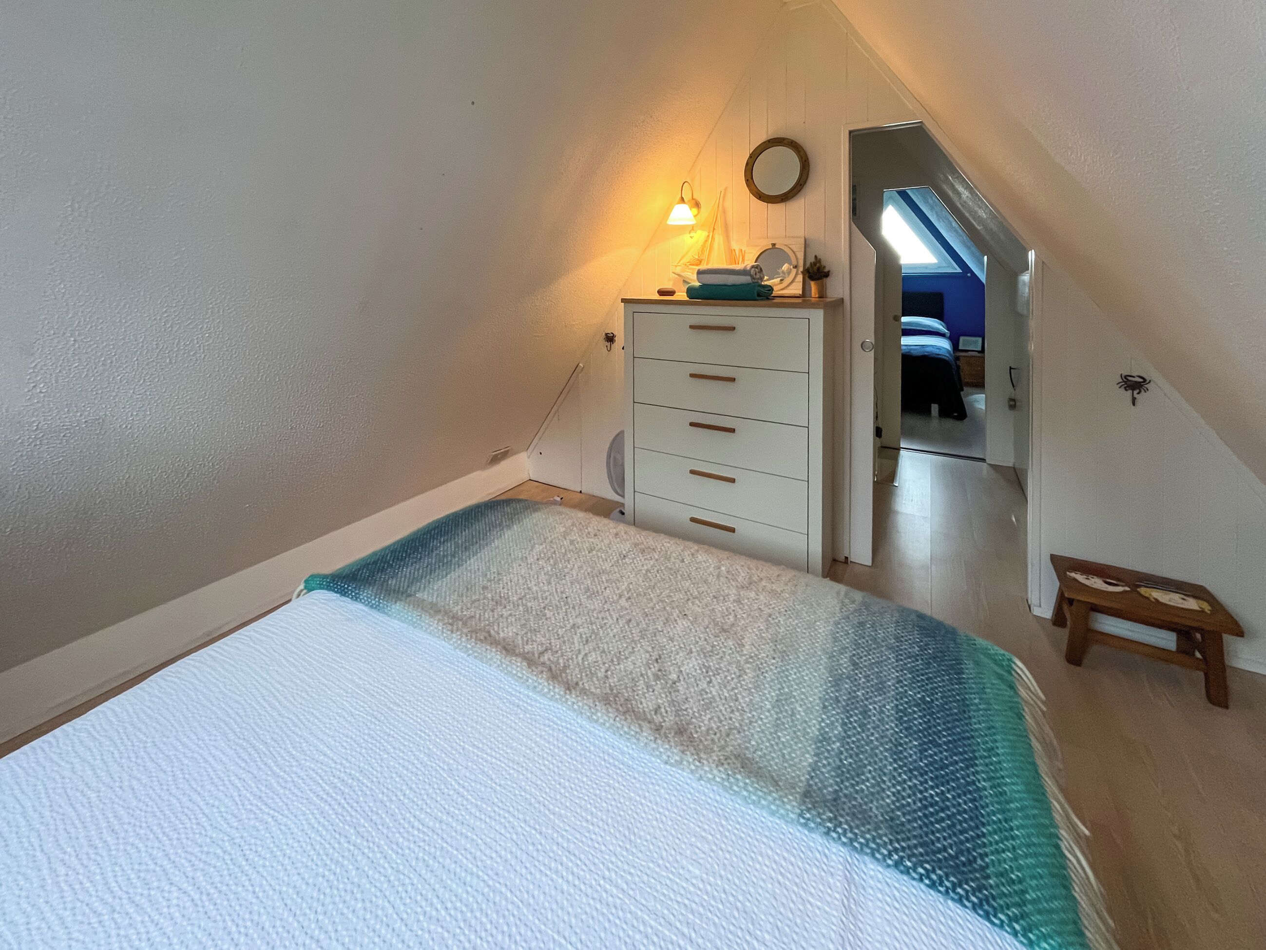 Ett sovrum med en säng, en byrå, en spegel och ett litet bord.